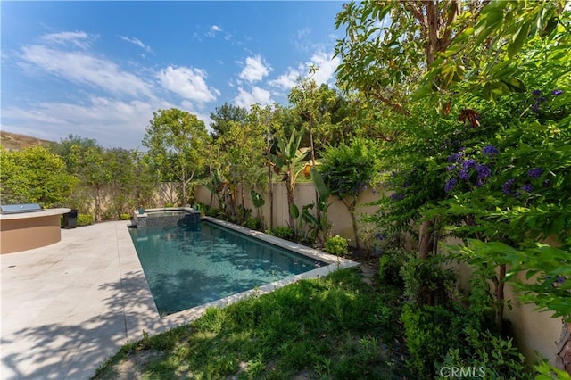 view of pool featuring a fenced backyard, a pool with connected hot tub, and a patio