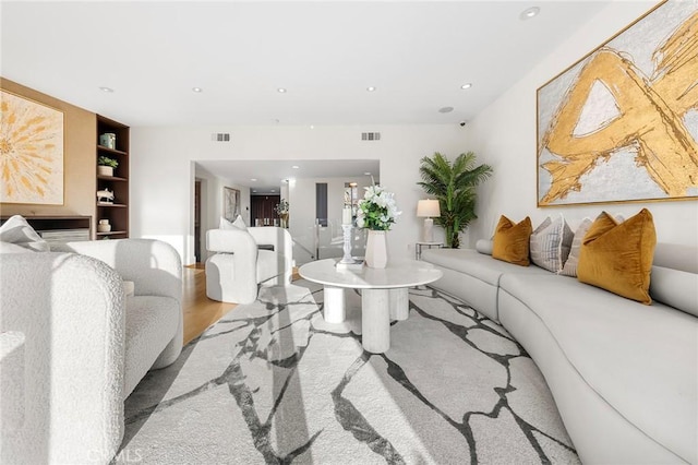 living room featuring light wood-type flooring and built in features