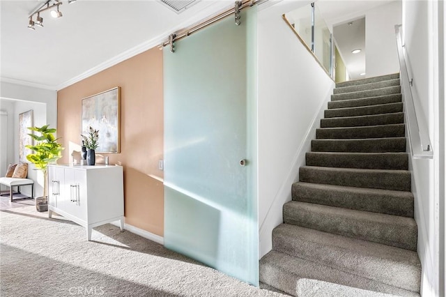 stairway with a barn door, carpet floors, and ornamental molding