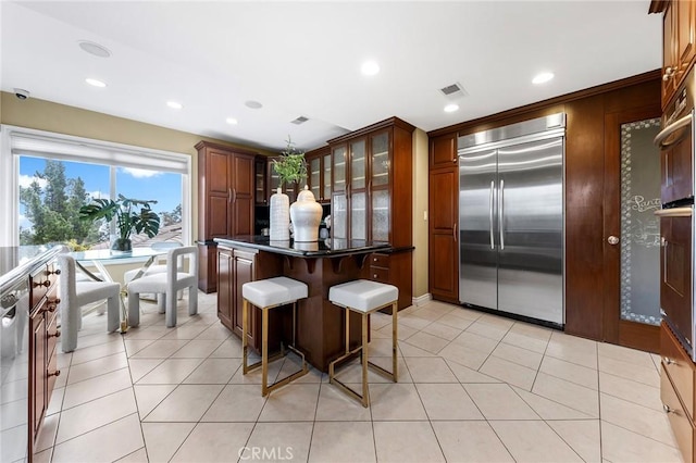 kitchen featuring a kitchen bar, appliances with stainless steel finishes, and light tile patterned floors