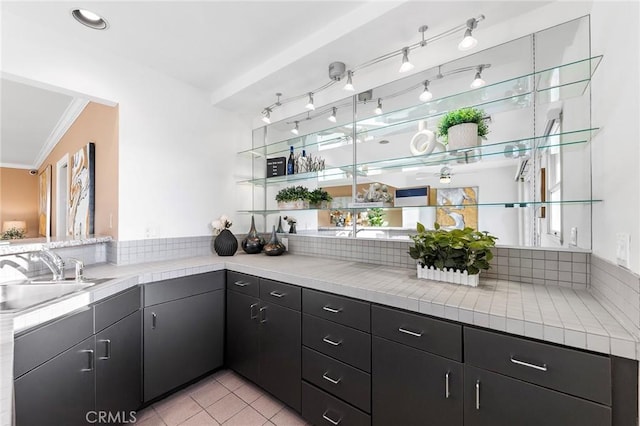 bar featuring light tile patterned flooring, sink, crown molding, and tile counters