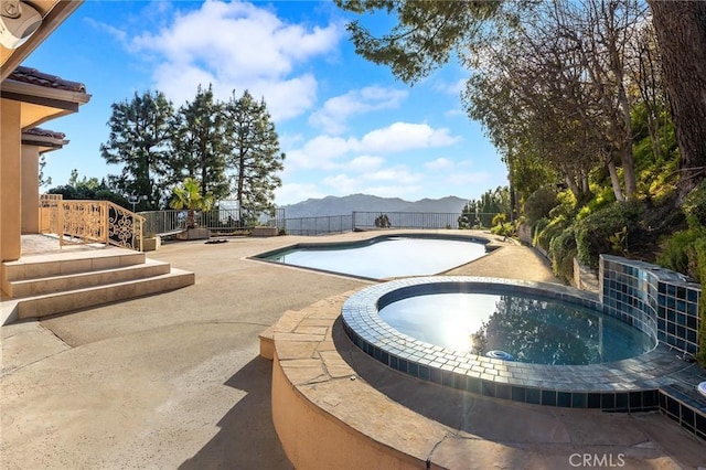 view of pool featuring an in ground hot tub, a mountain view, and a patio