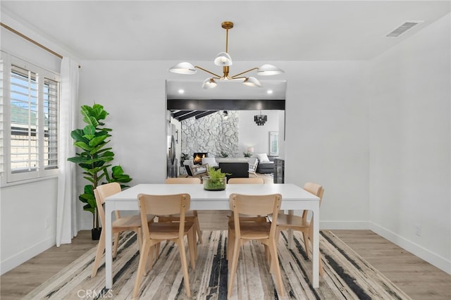 dining area with light hardwood / wood-style floors and a notable chandelier