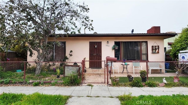 10813 State St, Lynwood, CA 90262 - bungalow-style house featuring stucco siding, a gate, a fenced front yard, and a chimney