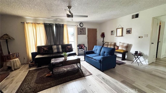 living area with a textured ceiling, visible vents, wood finished floors, and a ceiling fan