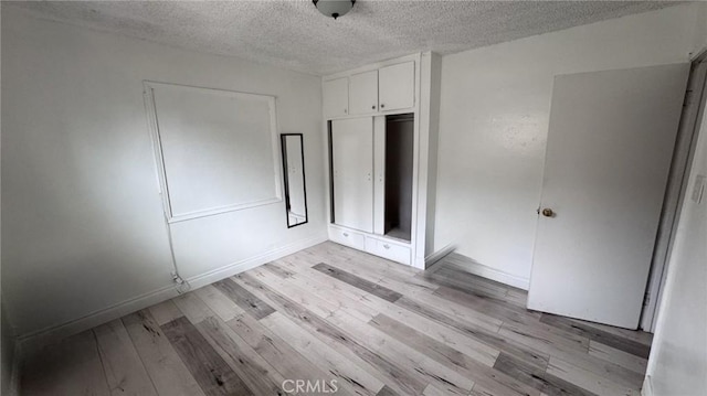 10813 State St, Lynwood, CA 90262 - unfurnished bedroom with a textured ceiling, light wood-type flooring, a closet, and baseboards