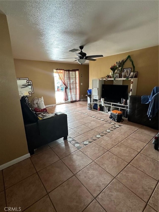 living room featuring ceiling fan, a textured ceiling, and tile patterned floors