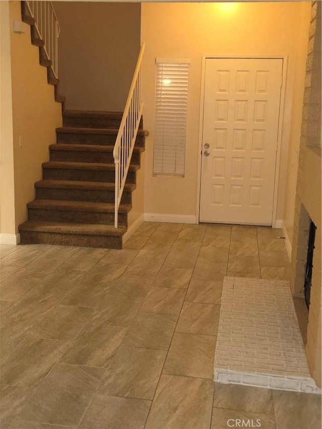 entryway with baseboards, a fireplace, and stairs