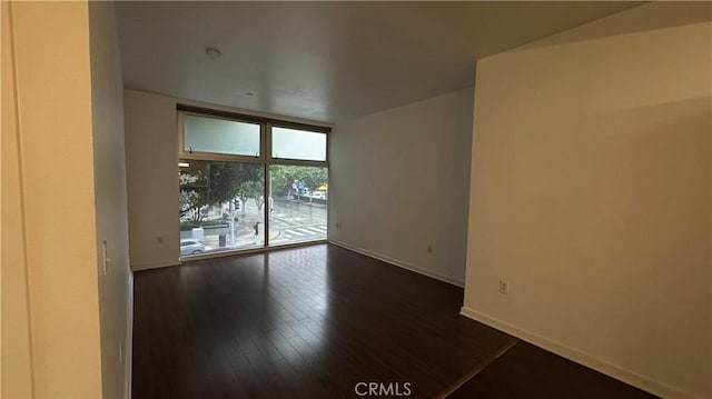 unfurnished room with baseboards, dark wood-style floors, and floor to ceiling windows