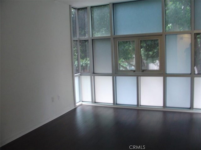 empty room with wood finished floors, baseboards, and a wealth of natural light
