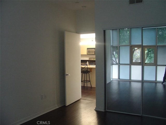 unfurnished room with baseboards, dark wood-type flooring, and visible vents