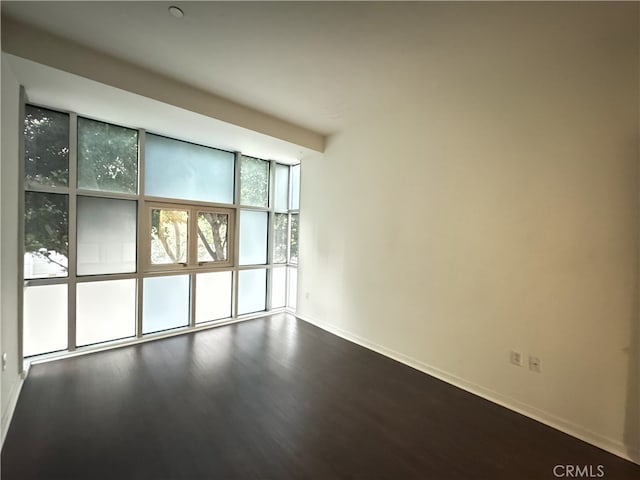 empty room with baseboards and dark wood-style flooring