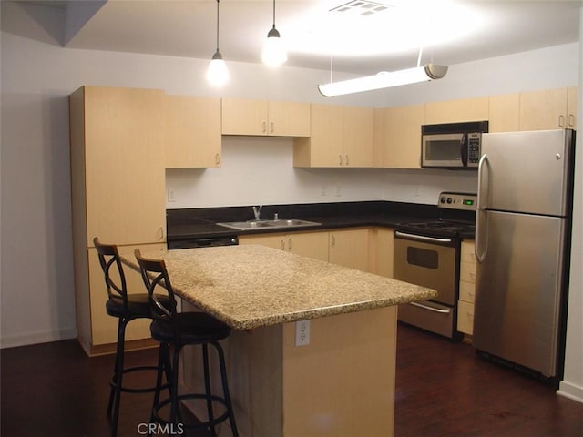 kitchen with visible vents, a sink, dark wood-type flooring, pendant lighting, and appliances with stainless steel finishes