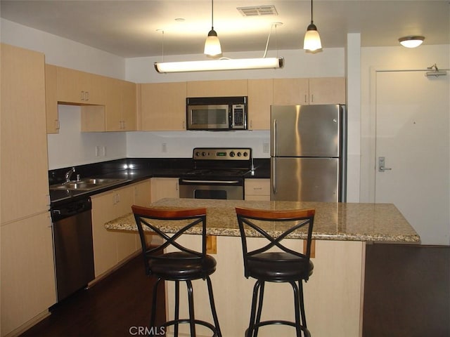 kitchen with a breakfast bar, visible vents, appliances with stainless steel finishes, and a sink