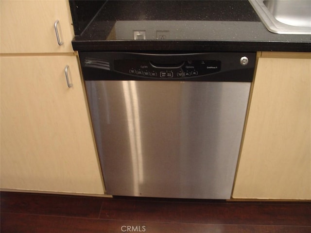 details with dark countertops, stainless steel dishwasher, a sink, and dark wood-type flooring