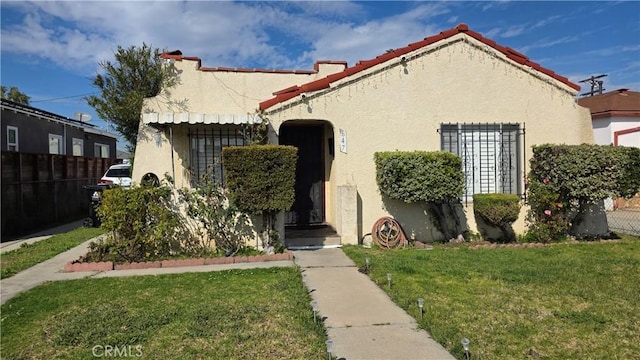 view of front facade featuring fence, a front lawn, and stucco siding