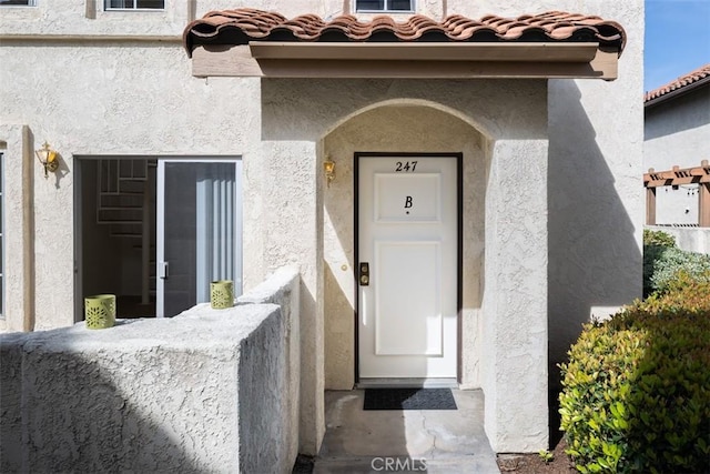 property entrance featuring a tile roof and stucco siding