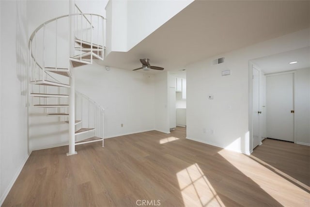 unfurnished living room with stairway, wood finished floors, visible vents, and baseboards