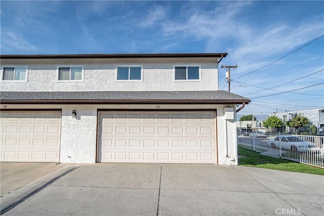 garage with fence and concrete driveway