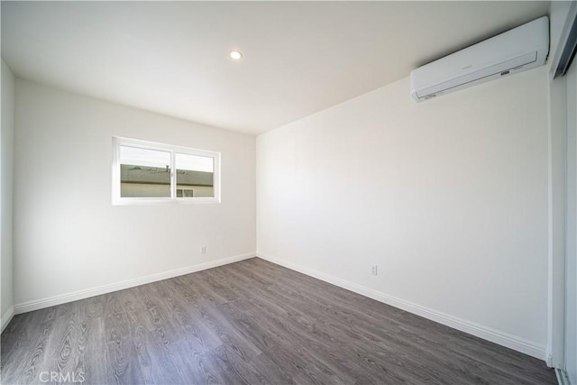 spare room with dark wood-style floors, recessed lighting, a wall mounted air conditioner, and baseboards