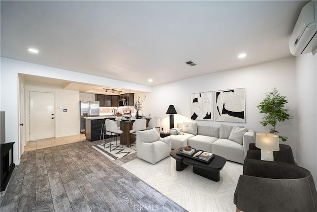 living area with recessed lighting, a wall mounted air conditioner, visible vents, and wood finished floors