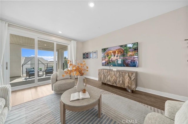 living area featuring baseboards, wood finished floors, and recessed lighting