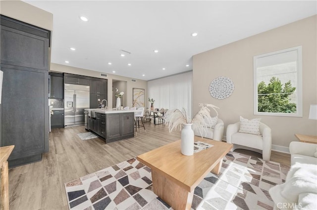 living area with light wood-style floors, recessed lighting, visible vents, and baseboards