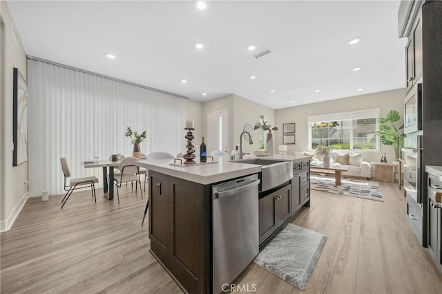 kitchen with stainless steel appliances, light countertops, a sink, and light wood finished floors