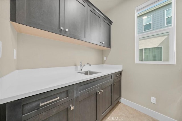 laundry area with a sink, baseboards, and light tile patterned floors