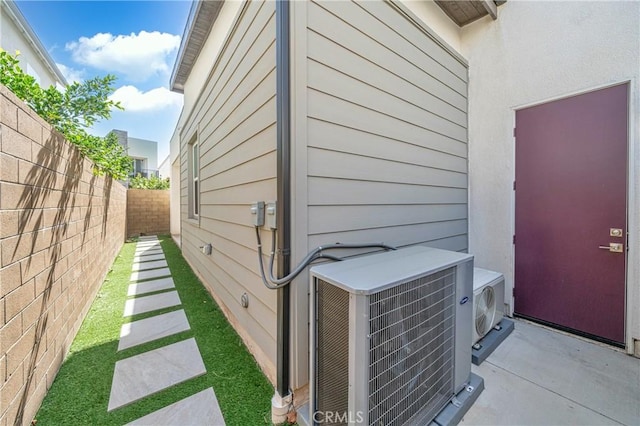 view of side of home with ac unit, cooling unit, a fenced backyard, and stucco siding