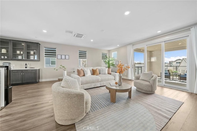 living room with light wood-type flooring, visible vents, indoor wet bar, and recessed lighting