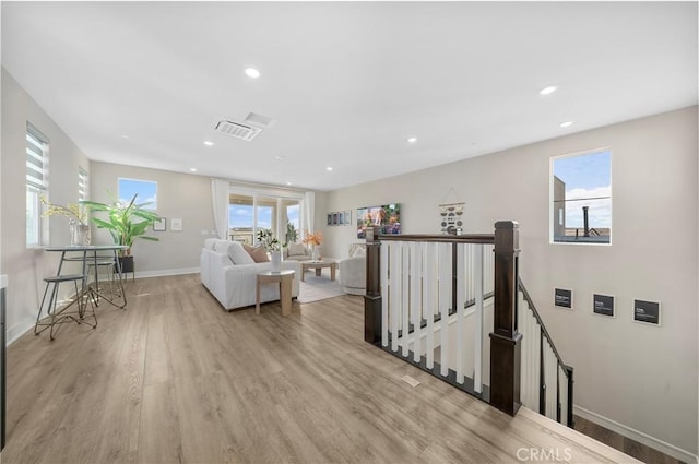 living room featuring light wood-style floors, baseboards, visible vents, and recessed lighting