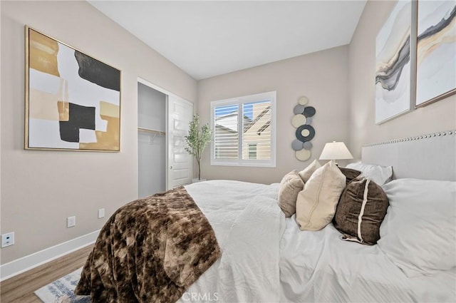 bedroom featuring a closet, wood finished floors, and baseboards