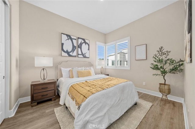 bedroom featuring light wood finished floors and baseboards