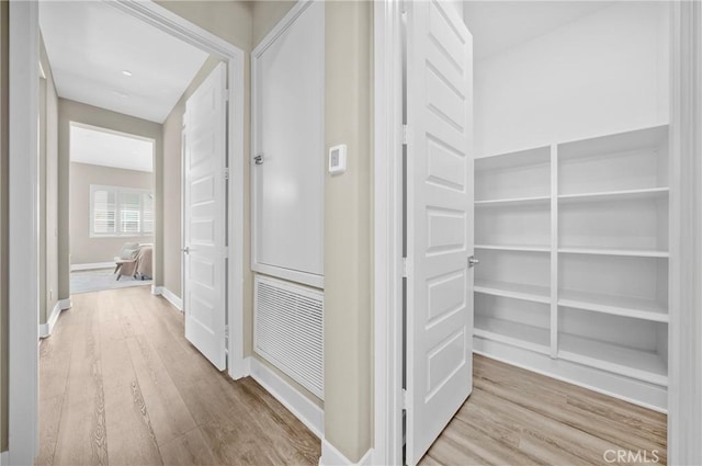 hallway featuring light wood-style flooring and baseboards