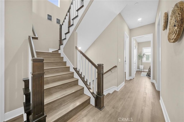 staircase with wood finished floors, visible vents, and baseboards