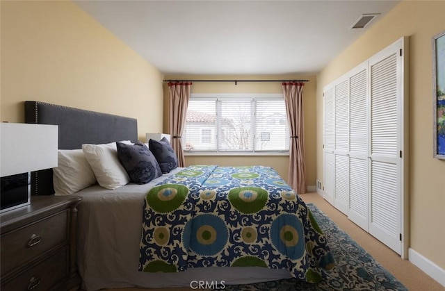 bedroom featuring visible vents, baseboards, a closet, and light carpet