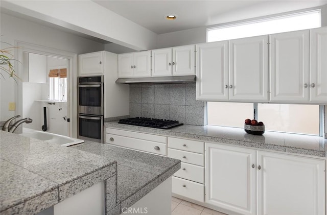 kitchen with a sink, double oven, black gas stovetop, and white cabinetry