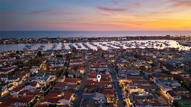 aerial view at dusk featuring a residential view and a water view