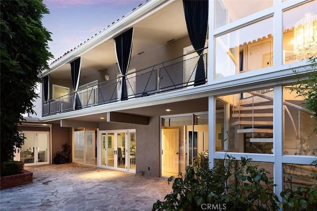 rear view of house featuring a patio, french doors, stucco siding, and a balcony