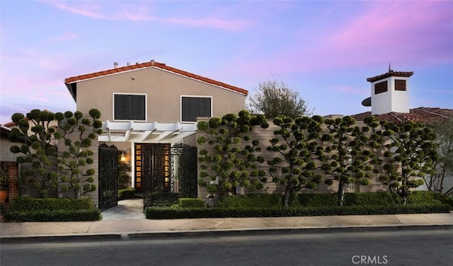 mediterranean / spanish-style home featuring a pergola, a gate, and stucco siding