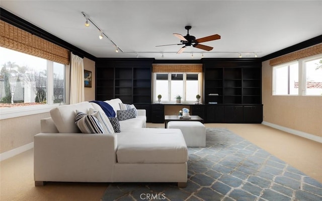 carpeted living area with baseboards, rail lighting, and ceiling fan