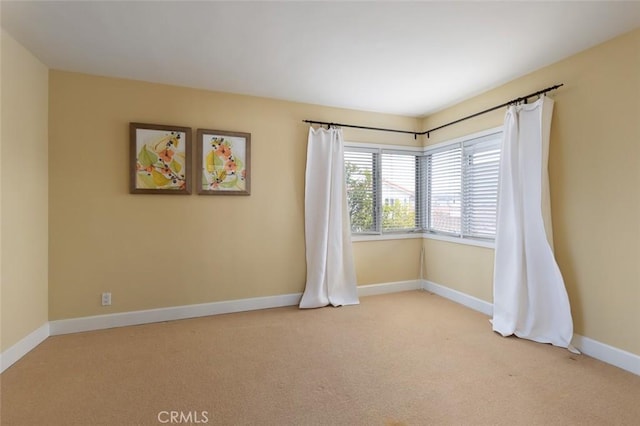 unfurnished room with light carpet and baseboards