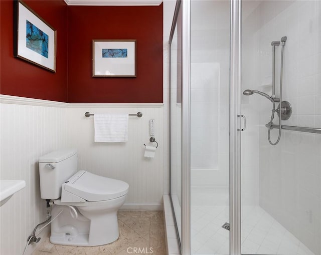 bathroom with toilet, a stall shower, tile patterned flooring, and wainscoting