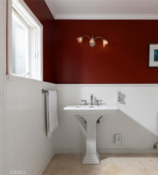 bathroom with crown molding, a wainscoted wall, and baseboards