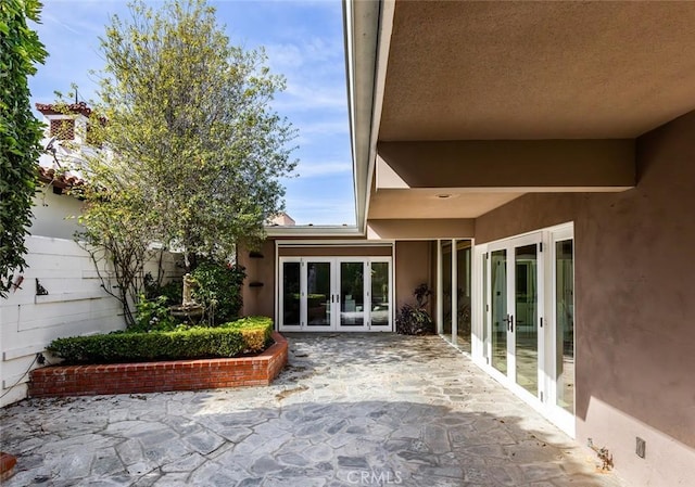 property entrance featuring french doors, a patio area, and stucco siding