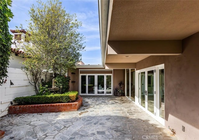 property entrance featuring a patio, stucco siding, and french doors