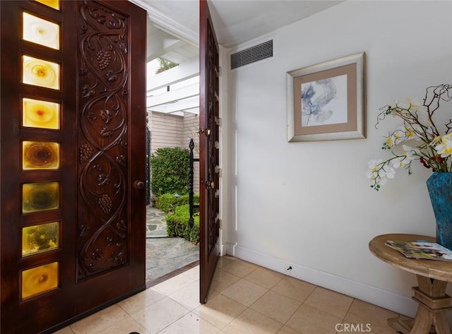 foyer with baseboards, light tile patterned floors, and visible vents
