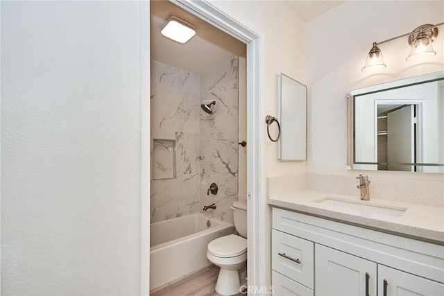 full bathroom featuring hardwood / wood-style flooring, tiled shower / bath combo, vanity, and toilet