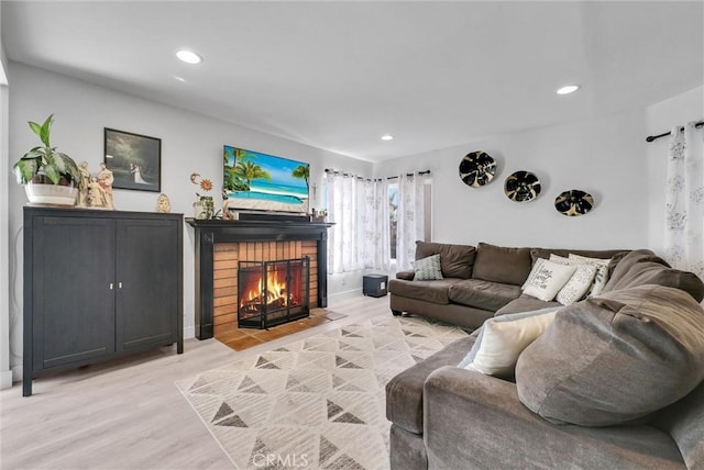 living area featuring light wood-type flooring, a fireplace, baseboards, and recessed lighting